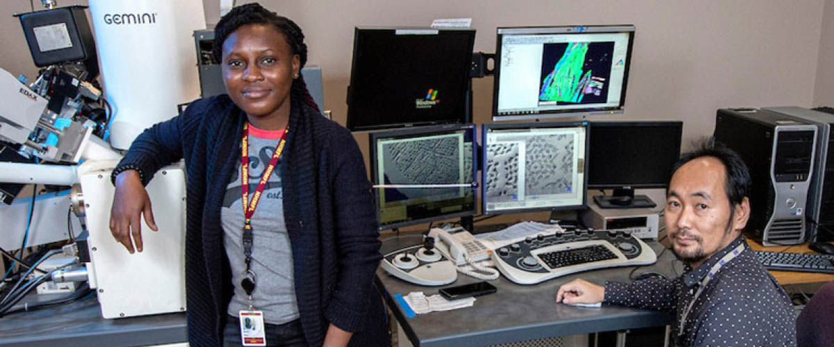 Abiola Temidayo Oloye, left, a fifth-year doctoral candidate and the lead author of a study published in Superconductor Science and Technology, at an electron microscope with Fumitake Kametani, an associate professor of mechanical engineering and principal investigator for the study at the FAMU-FSU College of Engineering.