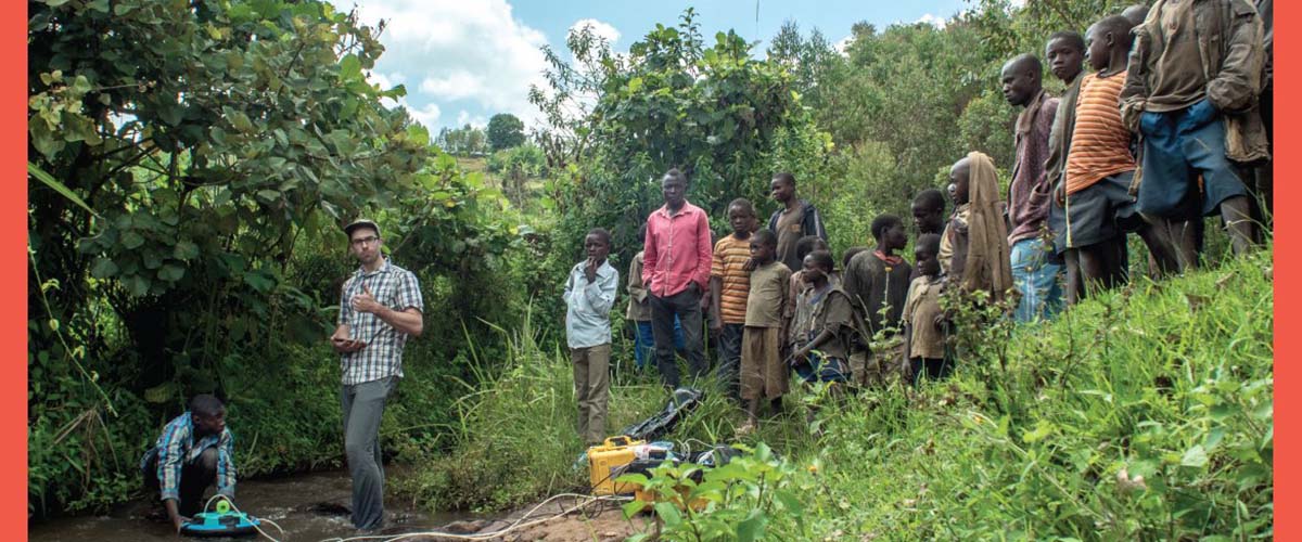 Area residents watch as Florida State University graduate student Travis Drake collects water samples from a stream in the Democratic Republic of Congo.