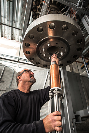 Research engineer Charles Lamar English inserts an early BiSSCO test coil into the furnace.