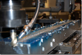 A milling machine is used to dig a groove into a bar of aluminum.