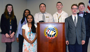 The six teens with K-12 outreach coordinator Carlos Villa at the podium.