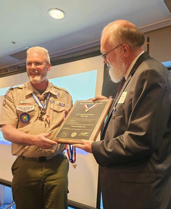Longtime scout leader Mike Boebinger, Greg's younger brother, presents him with the Distinguished Eagle Scout Award.