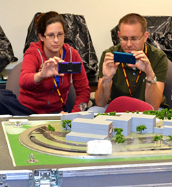 Adreanna Gimenez and Michael Myrga take pictures of a superconducting magnet train on a track.
