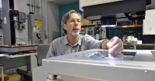Research Associate Bob Walsh examines the fracture surface of a tensile specimen on an inspection microscope in the Mechanical and Physical Properties Lab.