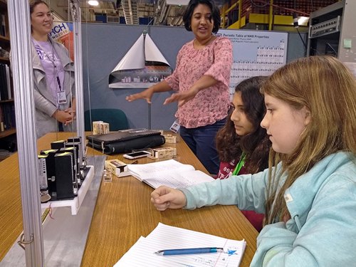 Mentors look on as their middle school students finish setting up their experiment