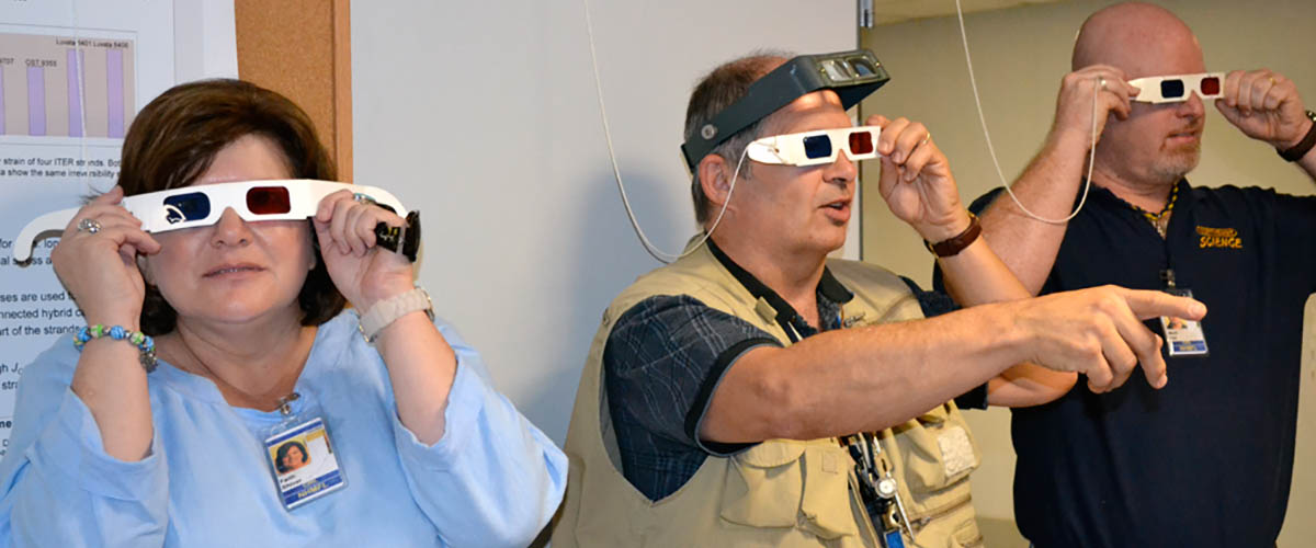 Scientist Bob Goddard (center) and two of the teachers he mentored use 3-D glasses to examine images outside his lab.
