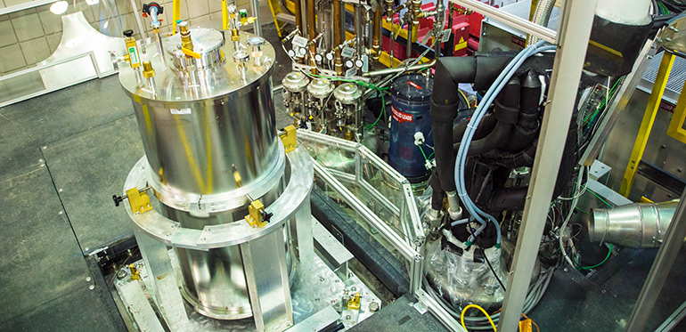 View of the cryostat mounted on top of the SCH (left) and cryogenic valves and supply lines to the SCH outsert magnet (background).