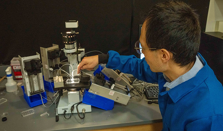 FSU chemistry professor Xiangpeng Li with his microfluidics system for droplet screening.