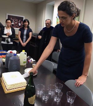 Paulino celebrates with cake and champagne after a successful dissertation defense.