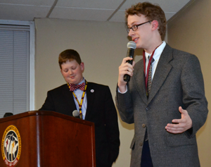 Student Grant Womble stands in the background as his partner, Quinn Huckaba, explains their microscope project.